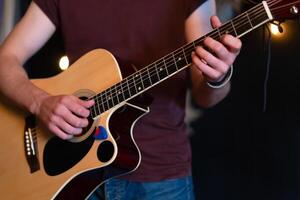 manlig musiker spelar akustisk gitarr. gitarrist spelar klassisk gitarr på skede i konsert stänga upp foto