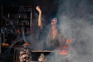halloween, häxa använda sig av magi bok och kittel förbereda förgifta eller kärlek trolldryck foto