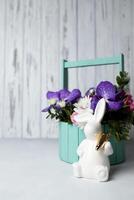 påsk kanin och bukett av blommor på betong tabell. kopia Plats foto