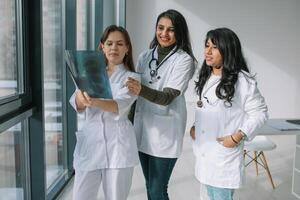 tre kvinnor doktorer av annorlunda races analysera de röntgen foto