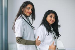 två ung indisk kvinna läkare ser på kamera i de sjukhus foto