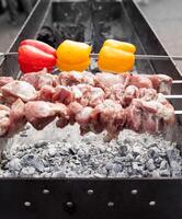 grillad kebab matlagning på metall grillspett. rostad kött kokta på utegrill. med röd och gul klocka peppar foto