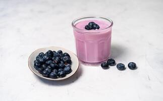 gott färsk blåbär yoghurt skaka efterrätt i glas stående på vit tabell bakgrund. foto