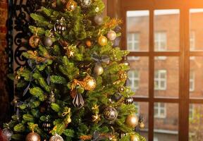 närbild av en jul träd dekorerad med guld bollar och blå bågar nära de fönster. jul Semester begrepp foto