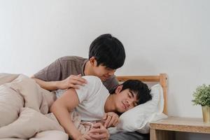 asiatiska gay par puss och kram på sängen hemma. unga asiatiska hbtq-män glada slappna av vila tillsammans spendera romantisk tid efter att ha vaknat i sovrummet hemma på morgonen koncept. foto