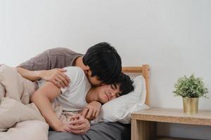asiatiska gay par puss och kram på sängen hemma. unga asiatiska hbtq-män glada slappna av vila tillsammans spendera romantisk tid efter att ha vaknat i sovrummet hemma på morgonen koncept. foto