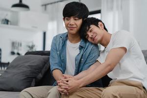 porträtt ungt asiatiskt gay par känner sig glada leende hemma. asiatiska lgbtq-män slappna av tandigt leende tittar på kameran medan de ligger på soffan i vardagsrummet hemma på morgonkonceptet. foto