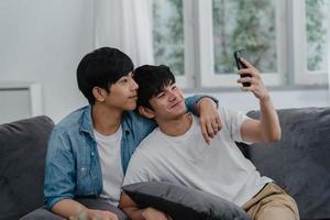 asiatisk influencer gay par vlogg hemma. asiatiska lgbtq män glada slappna av kul med teknik mobiltelefon spela in livsstil vlogg video uppladdning i sociala medier medan du ligger soffa i vardagsrum koncept. foto