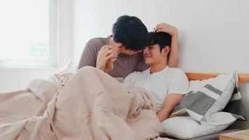 stilig asiatisk gay par pratar på sängen hemma. ung asiatisk lgbtq kille glad slappna av vila tillsammans spendera romantisk tid efter att ha vaknat i sovrummet på modernt hus på morgonen koncept. foto