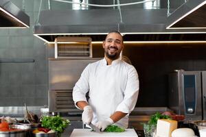 stilig ung afrikansk kock stående i professionell kök i restaurang framställning en måltid av kött och ost grönsaker. foto