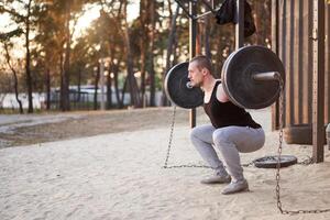 man med skivstång utomhus- Gym på natur i parkera. foto