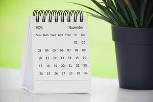 november 2024 skrivbord kalender med inlagd växt på en skrivbord med grön bakgrund. foto