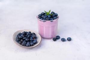 gott färsk blåbär yoghurt skaka efterrätt i glas stående på vit tabell bakgrund. foto