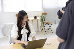 en arbetssätt japansk kvinna med fotograf i de Hem kontor närbild foto