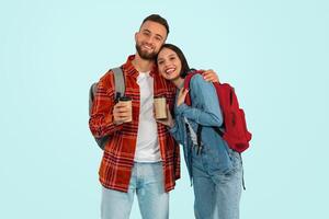 Lycklig ung studenter par stående tillsammans med hämtmat kaffe, studio foto