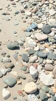 ai genererad lugn strand scen med spridd grå småsten på de sand vertikal mobil tapet foto