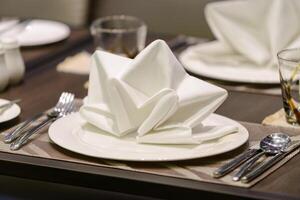 vit servett dekorerad på middag uppsättning tabell i restaurang foto