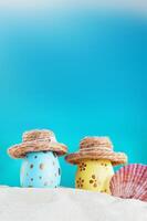 gul och blå ägg med polka punkt i hatt med trumpetsnäcka på strand förbi hav på solig dag. påsk, resa, semester. vertikal. kopia Plats foto