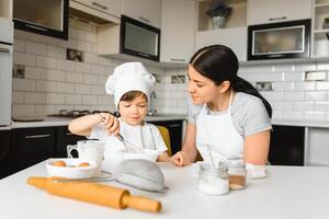 Lycklig familj. mor undervisning henne son på vilket sätt till matlagning kaka meny i morgon. friska livsstil begrepp.. bakning jul kaka och laga mat begrepp foto