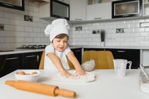 pojke i laga mat hatt Sammanträde på en kök disken. liten pojke i kök foto