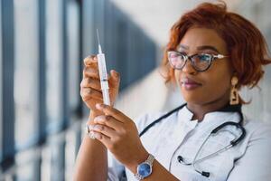 afrikansk amerikan kvinna läkare innehav spruta med injektion foto