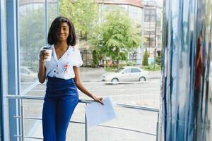 företag svart kvinna innehav en kopp av kaffe och filer foto
