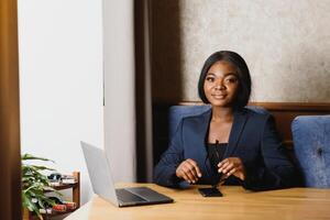 Lycklig ung afrikansk amerikan affärskvinna använder sig av dator i kontor foto