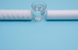 vatten filter. kol patroner och en glas på en blå bakgrund. hushåll filtrering systemet. foto