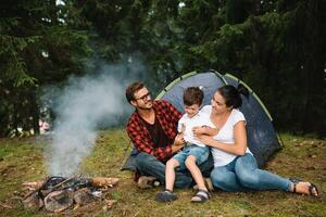 familj nära de brand i de skog. förälder med barn på en tält bakgrund. nationell parkera. vandra med barn. aktiva sommar högtider foto