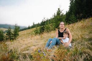 ung mamma med bebis pojke reser. mor på vandring äventyr med barn, familj resa i berg. nationell parkera. vandra med barn. aktiva sommar högtider. foto