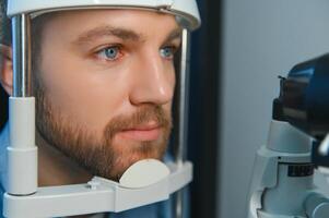 vuxen man syn testa med binokulär slits-lampa. kontroll näthinnan av en manlig öga närbild. oftalmologi klinik foto