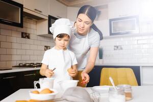 Lycklig familj. mor undervisning henne son på vilket sätt till matlagning kaka meny i morgon. friska livsstil begrepp.. bakning jul kaka och laga mat begrepp foto