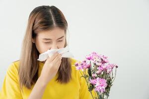 pollen allergier, asiatisk ung kvinna nysning i en näsduk eller blåser i en torka, allergisk till vild vår blommor eller blommar under vår. allergisk reaktion, respiratorisk systemet problem foto