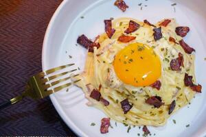 carbonara pasta med ägg på topp, parmesan ost och grädde sås. traditionell italiensk kök foto