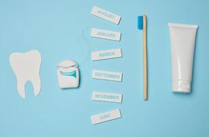 rör med tandkräm, dental flock och tandborste på en blå bakgrund, oral hygien. foto