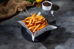 traditionell ohälsosam snabb mat potatis pommes frites frites i djup fritös med svart peppar topp se på mörk bakgrund foto