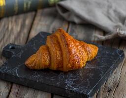 choklad croissant eras i en maträtt isolerat på skärande styrelse sida se av frukost på trä- bakgrund foto