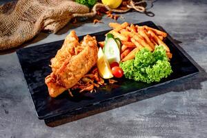 pacific dory fisk biff med frites och sallad i en maträtt sida topp se på mörk bakgrund foto