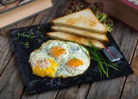 solig sida upp ägg med skivad bröd eras i en maträtt isolerat på skärande styrelse sida se av frukost på trä- bakgrund foto