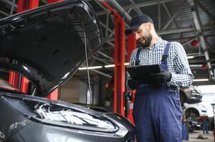 leende mekaniker skrivning på Urklipp på de reparera garage foto