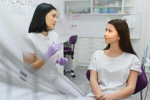 människor, medicin, stomatologi och hälsa vård begrepp - Lycklig kvinna tandläkare med patient flicka talande på dental klinik kontor foto