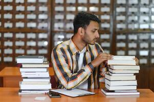 Lycklig smart indisk eller arab kille, blandad lopp manlig, universitet studerande, i de bibliotek foto