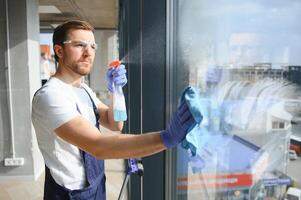 ett anställd av en professionell rengöring service tvättar de glas av de fönster av de byggnad. monter rengöring för butiker och företag. foto