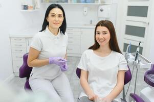 människor, medicin, stomatologi och hälsa vård begrepp - Lycklig kvinna tandläkare med patient flicka talande på dental klinik kontor foto