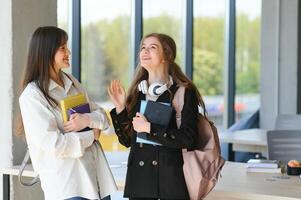 utbildning. två duktig modern studenter i svart och vit enhetlig studie i en bibliotek Sammanträde på en tabell med böcker. modern generation. studenter. foto