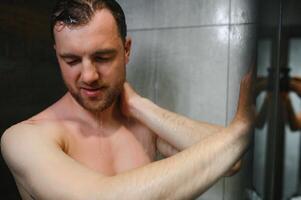 avkopplande efter stressig dag. midja upp porträtt av naken muskulös herre tar dusch på Hem. foto