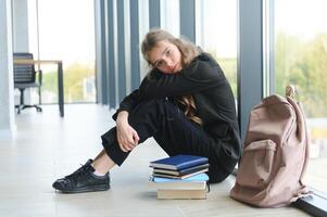 upprörd tonåring flicka sitta på golv tyvärr se ut fönster orolig handla om Tonårs problem på skola och kommunikation med förälder. orolig flicka spänd lida handla om mobbning på skola foto