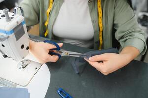 Lycklig kvinna sömmerska arbetssätt med sömnad maskin på textil- fabrik. foto