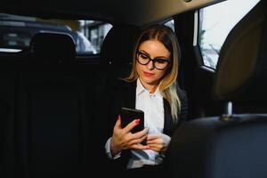 några sortera av intressant information. smart affärskvinna sitter på baksätet av de lyx bil med svart interiör. foto