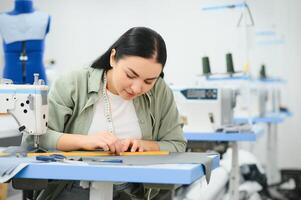 Lycklig kvinna sömmerska arbetssätt med sömnad maskin på textil- fabrik. foto